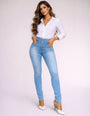 Mulher vestindo calça modeladora jeans azul clara e camisa social branca de manga longa.