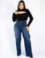 Mulher usando calça jeans modeladora cintura alta e blusa preta de manga longa.
