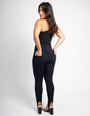 Mulher usando calça modeladora preta de cintura alta e top preto, vista traseira em estúdio.