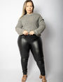 Mulher usando calça modeladora preta de cintura alta e suéter cinza, moda plus size.