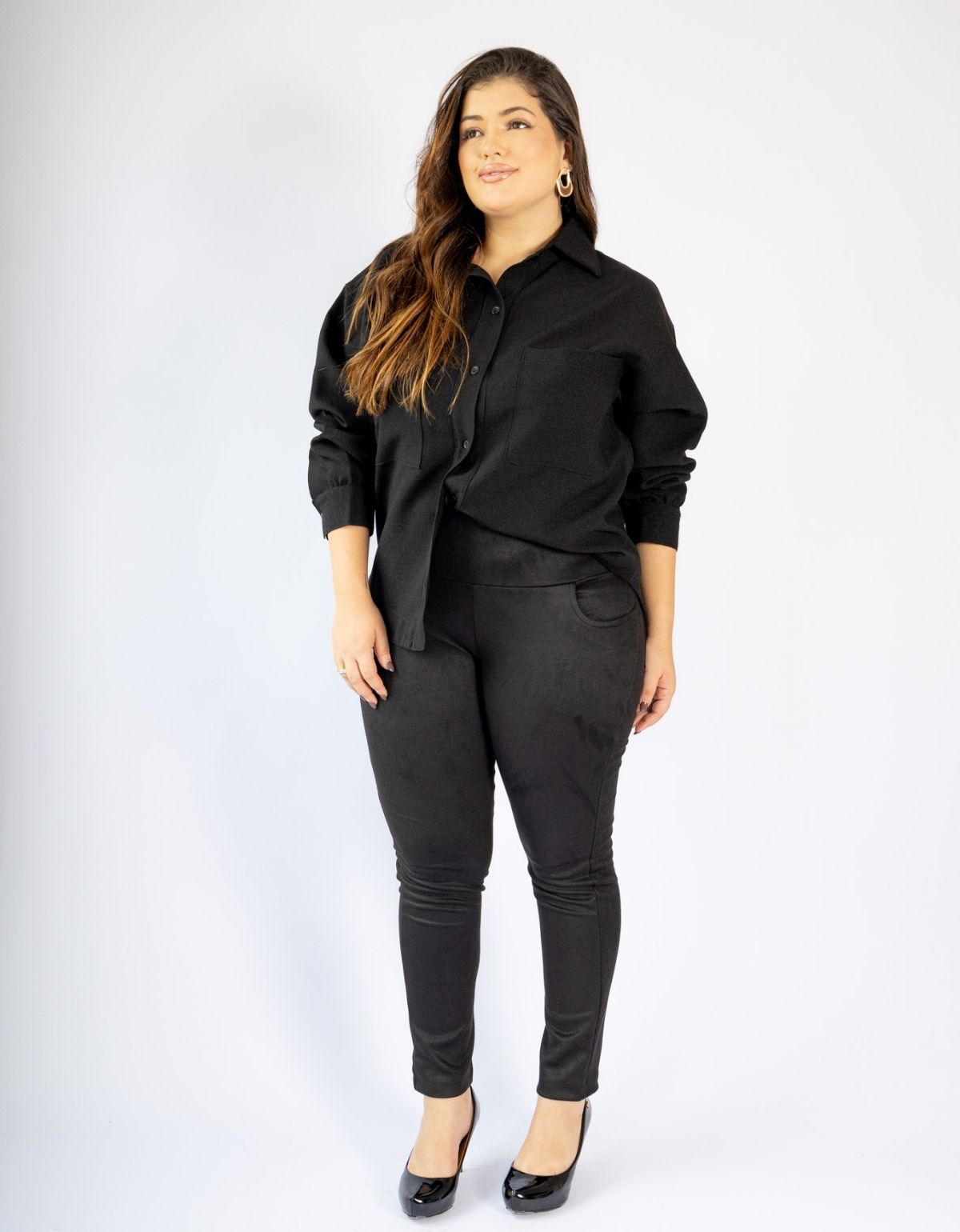 Mulher com modelador preto de manga longa e calça leggings modeladora, em fundo branco.