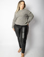 Mulher vestindo calça modeladora preta de courino e suéter cinza, moda plus size.