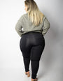 Mulher de costas vestindo calça modeladora preta e suéter cinza, moda plus size