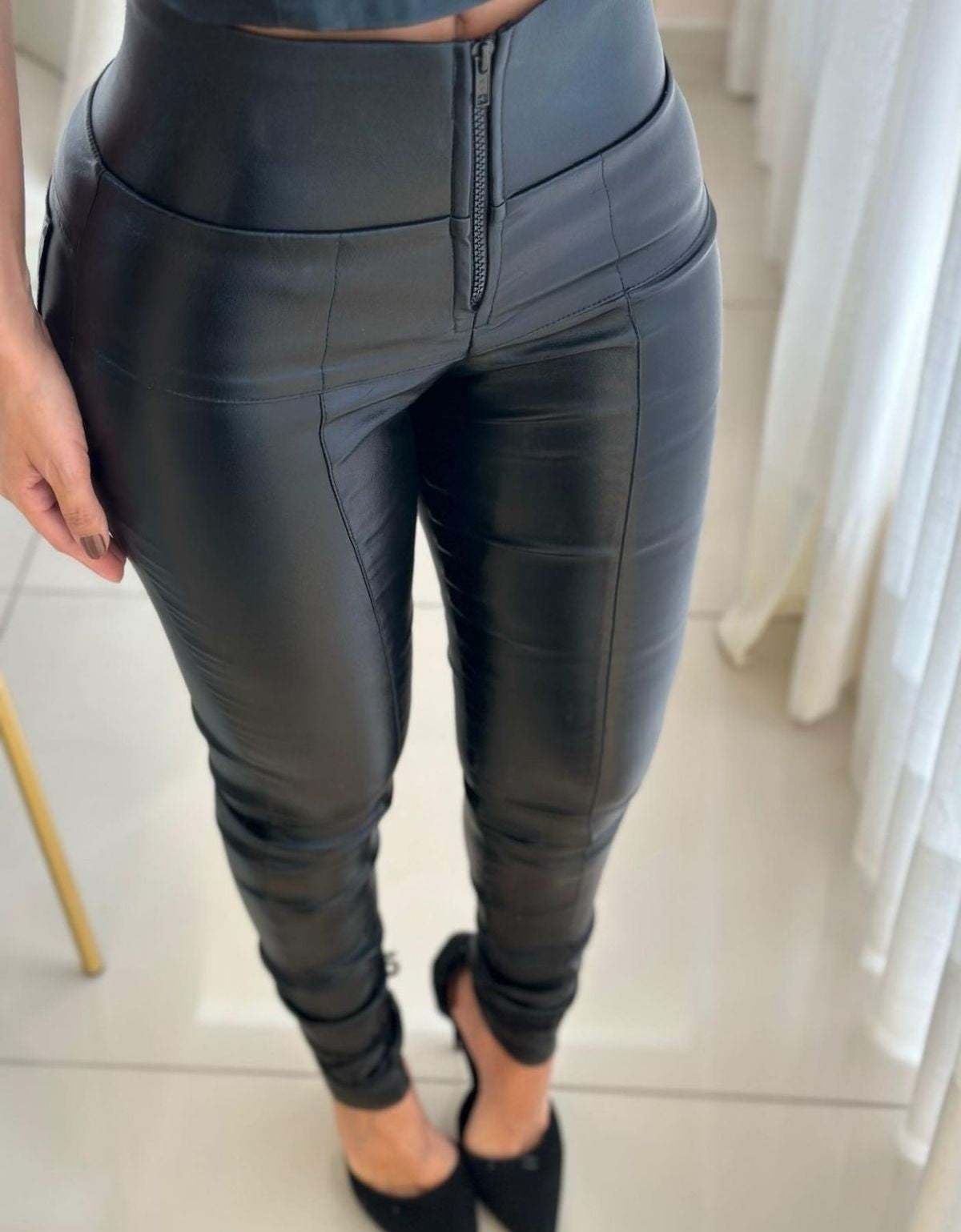 Calça modeladora preta feminina de cintura alta, com zíper frontal, tecido ajustado ao corpo.