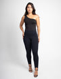 Mulher vestindo body preto de um ombro só e leggings preta modeladora, fundo branco.